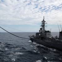 The Maritime Self-Defense Force helicopter carrier Izumo (left) is refueled by the MSDF destroyer Sazanami during a military exercise in the South China Sea on June 20. One year after the South China Sea ruling, a deceiving calm