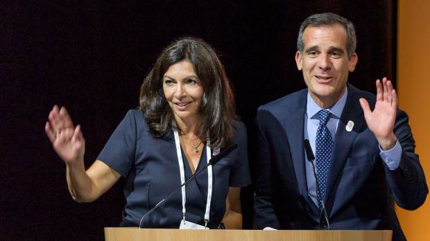 Paris Mayor Anne Hidalgo (left) and Los Angeles Mayor Eric Garcetti wave from the podium during an IOC extraordinary session on Tuesday in Lausanne, Switzerland. IOC ready to award Paris, L.A. next two Olympics