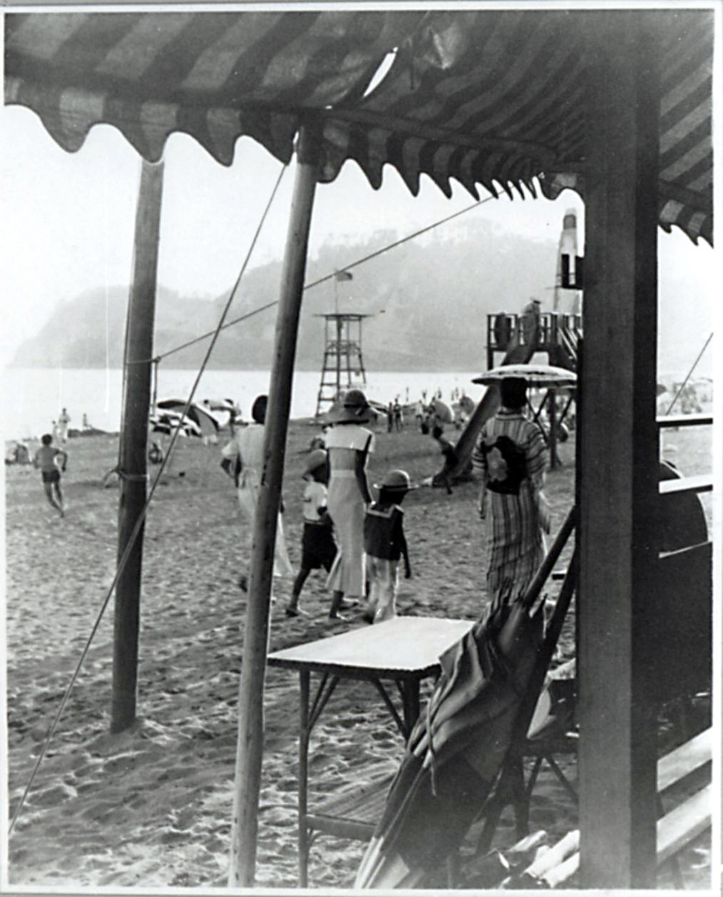 An image from the 1930s, of ladies and children on a beach near Kamakura with Enoshima island in the background. | ARCHIVE OF THE KAMAKURA CITY CENTRAL LIBRARY