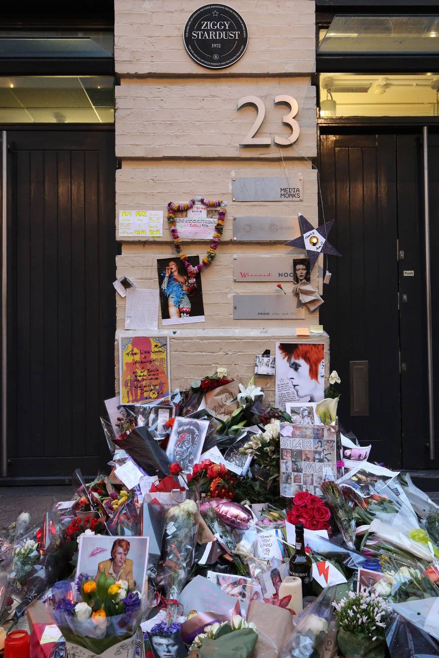 Flowers are left beneath a plaque marking the location of the cover photo for Bowie’s 