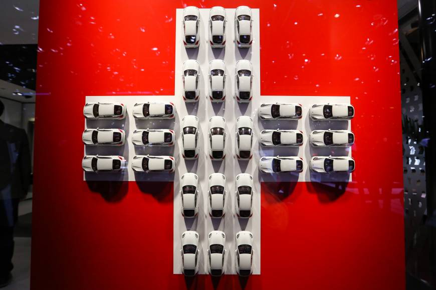 Model white cars sits in a cross formation of the Swiss national flag on the second day of the 86th Geneva International Motor Show in  Switzerland on Wednesday. The show opened to the public on March 3.