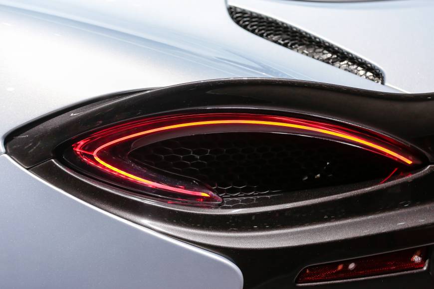 The illuminated rear lights on a McLaren 570GT luxury automobile, manufactured by McLaren Automotive Ltd., at the Geneva International Motor Show.