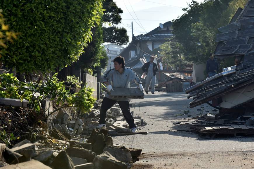 A man clears the debris of a broken wall in Mashiki, Kumamoto Prefecture on Saturday.  