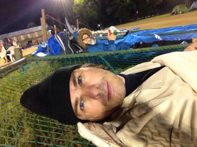 Sean Michael Wilson gets some rest on a pushed-down fence after evacuating in Kumamoto.