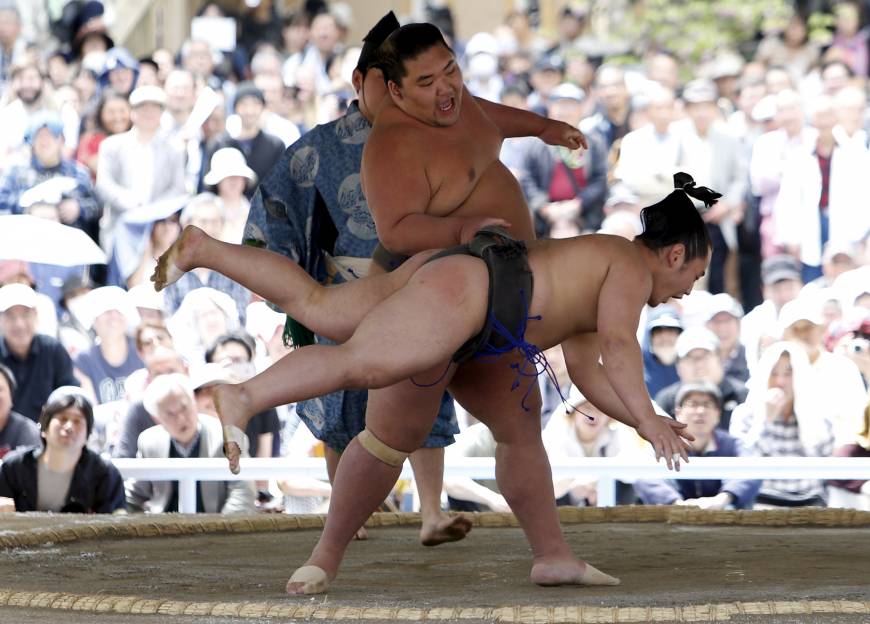 A sumo wrestler sends this opponent flying during a Honozumo bout at Yasukuni Shrine on Monday.