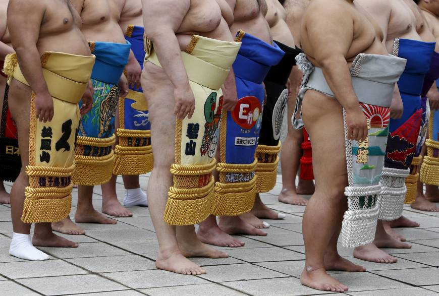 Sumo wrestlers wearing colorful and ornate kesho-mawashi, which often bear the names of corporate sponsors, assemble to pray before the start of the  Honozumo.