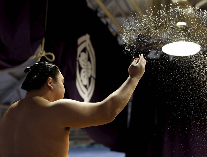 Mongolia-born grand sumo champion Hakuho throws salt, which is believed to purify the ring before a bout.