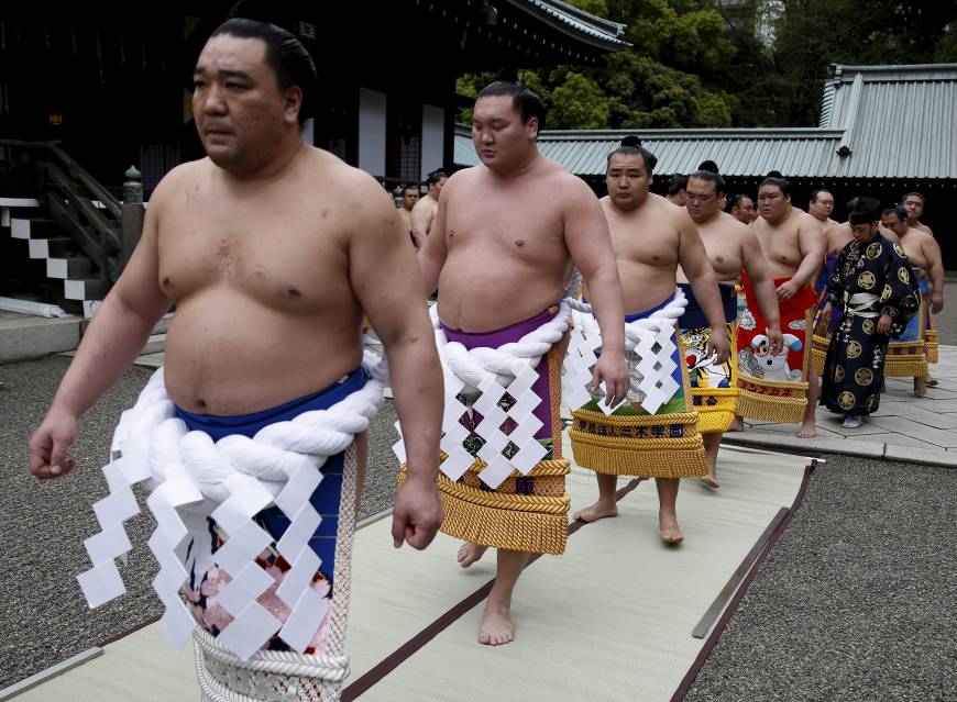 After prayer, yokozuna wearing tsuna — thick rope decorated with paper that alludes to lightning — exit the shrine and head for the ring.