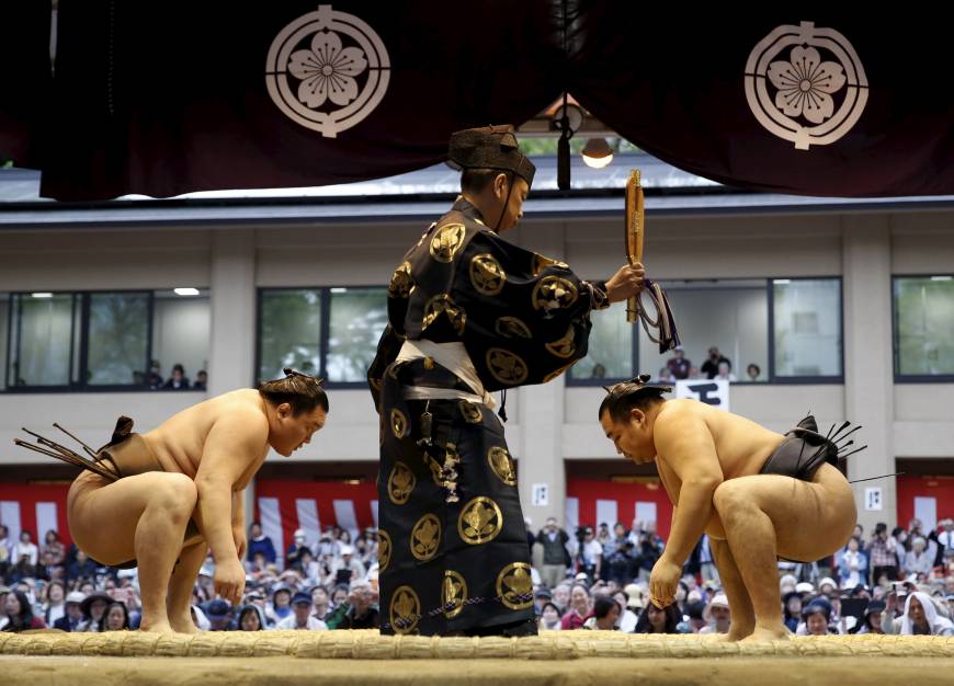 A referee stands between Mongolia-born grand sumo champions Hakuho (left) and Kakuryu  as they face off before a exhibition bout.