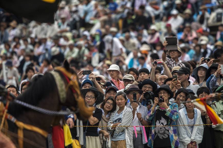 Spectators photograph samurai horseman in the Kacchu Keiba race during the Soma Nomaoi festival in Minamisoma, Fukushima Prefecture, on Sunday.