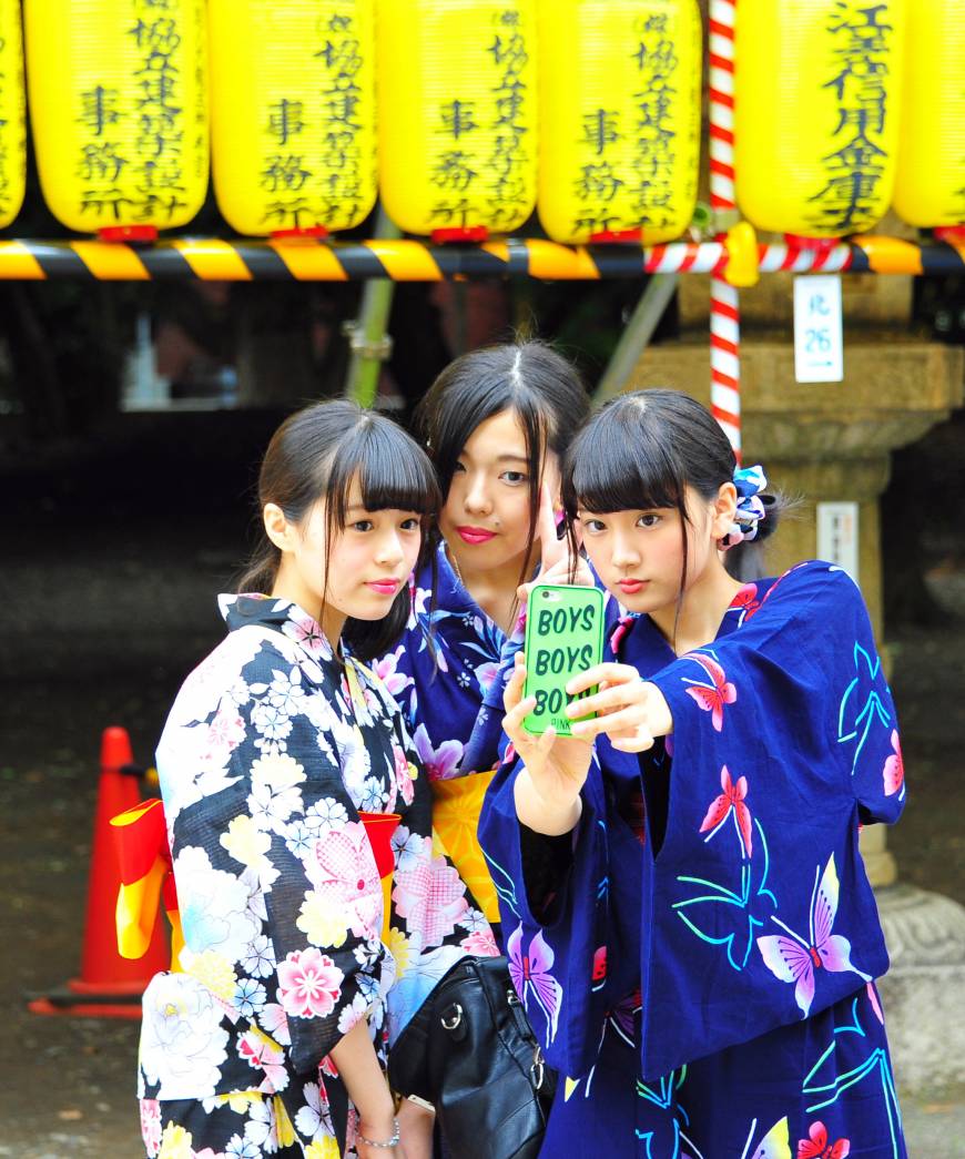 Women in yukata casual kimono take a selfie with their smartphone at the Mitama Matsuri festival at Yasukuni Shrine in Tokyo
