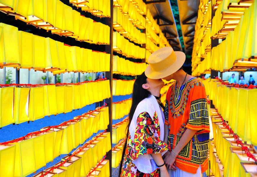 A couple kiss among rows of orange lanterns at the Mitama Matsuri festival at Yasukuni Shrine in Tokyo