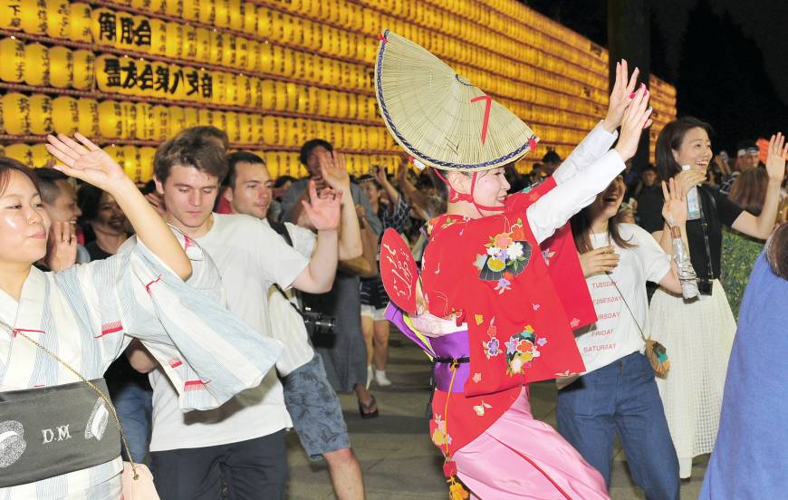 Tourists from home and abroad dance with Bon odori performers during the Mitama Matsuri festival at Yasukuni Shrine in Tokyo