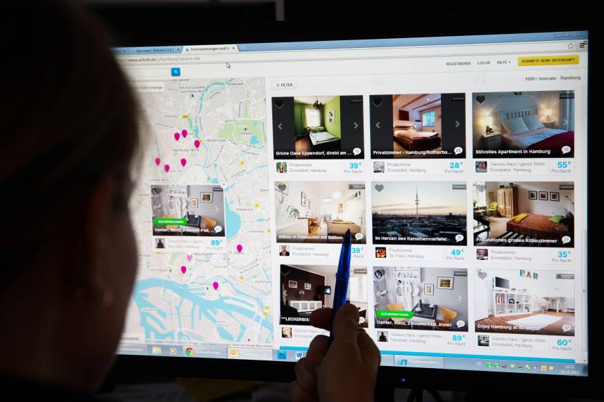 A woman browses places to stay on the Airbnb website. 