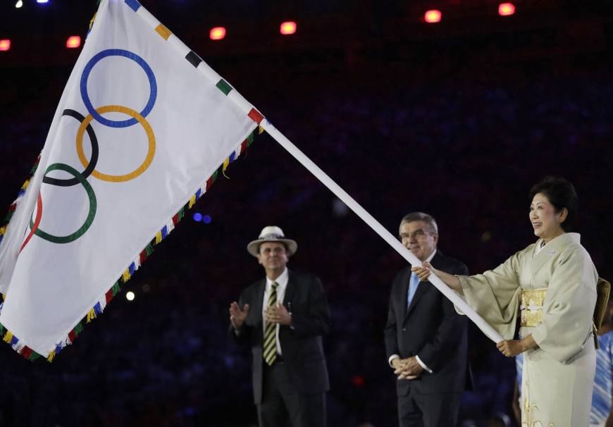 Tokyo Gov. Yuriko Koike waves the Olympic flag as Rio de Janeiro Mayor Eduardo Paes (left) and IOC President Thomas Bach watch during the 2016 Summer Olympics closing ceremony in late August. 