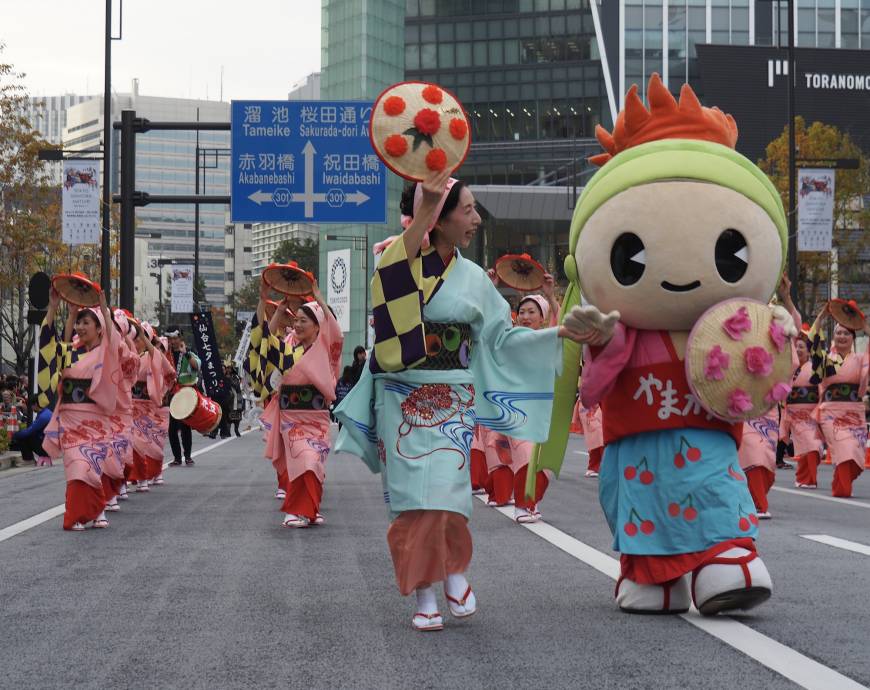 A lead performer of Yamagata Hanagasa guides the mascot Hangata Beni-chan, who wears a costume touting the prefecture