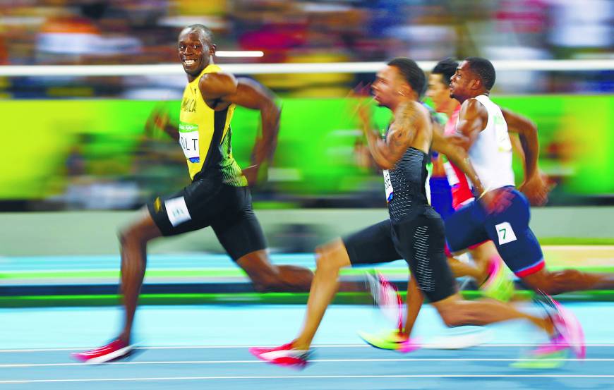 Jamaican sprinter Usain Bolt turns to look at Canada’s Andre De Grasse during the men’s 100-meter semifinals.