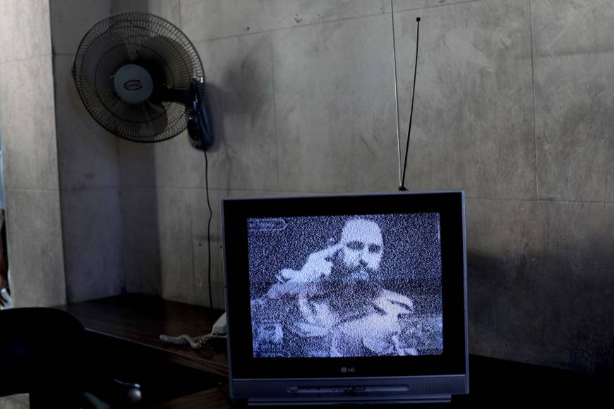 A TV broadcasts black-and-white footage of Fidel Castro at a memorial on the outskirts of Havana.