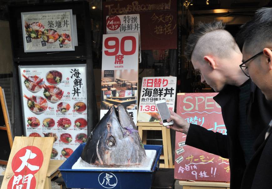 A tourist photographs the head of a freshly caught tuna at a sushi restaurant in Tsukiji, Tokyo.
