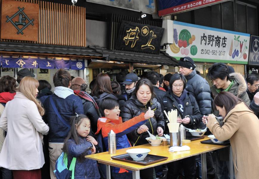 A family enjoys noodles at one of the many stalls offering traditional Japanese food.