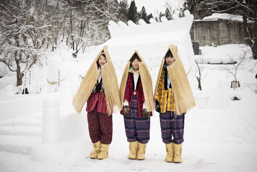 Women in traditional work pants stand in front of a shrine at the Inukko festival in Yuzawa in 2015.