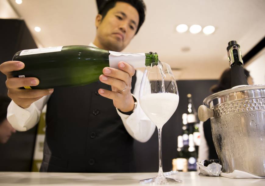 A member of the Japan Awasake Association pours a glass of Nanbu Bijin Asa Wake Sparkling sake, brewed by Nanbu Bijin Co., during a Sake Marche event at the Isetan Shinjuku department store in Tokyo on June 28.
