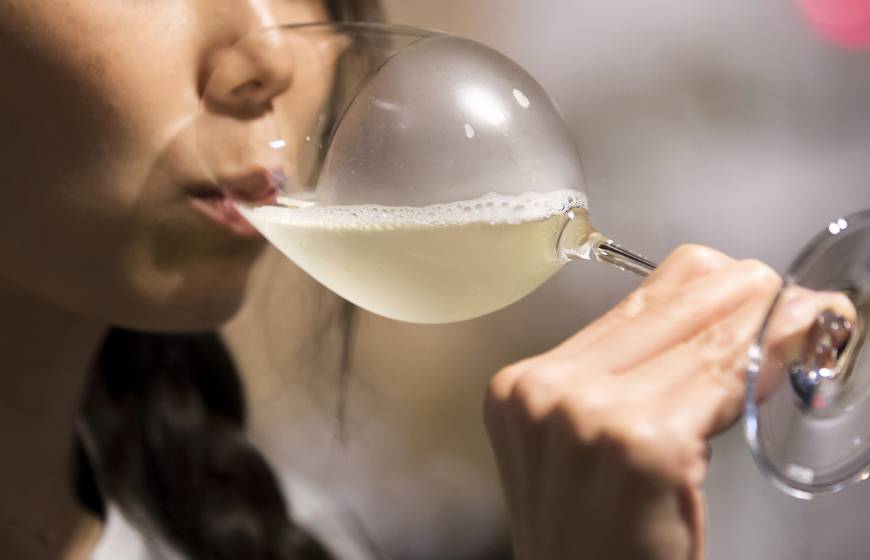 A customer drinks a glass of sparkling sake at the Japan Awasake Association booth during a Sake Marche event at the Isetan Shinjuku department store in Tokyo on June 28.