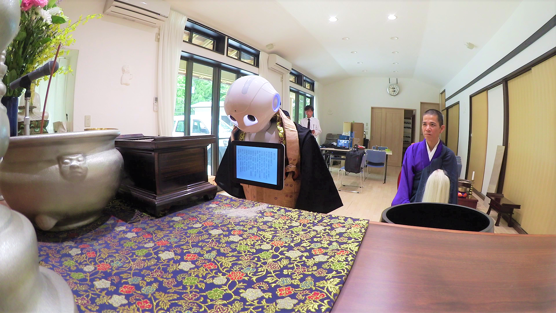 Pepper, the robot created by SoftBank Robotics, bows during a Buddhist ritual with a monk at a temple in Yokohama on July 20. Nissei Eco Co. has programmed Pepper to recite sutras as part of its expanded funeral service business. | COURTESY OF NISSEI ECO CO.