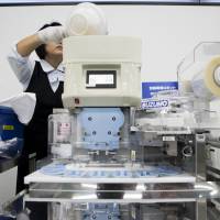 An employee puts a bowl of rice into a Suzumo Machinery Co. sushi machine during a demonstration. | BLOOMBERG