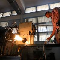 Engineering student Mostafa Saeed Ali works near flame used in the process of burning car tires into diesel in Cairo Wednesday. | REUTERS