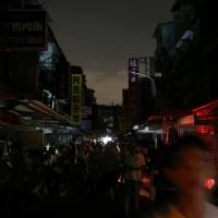 People walk on a street during a massive power outage in Taipei on Aug. 15. | REUTERS