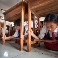 Pupils protect themselves under a table during a tsunami drill at Tanjung Benoa school in Badung, Indonesia\'s Bali resort island, Tuesday. | ANTARA FOTO / NYOMAN BUDHIANA / VIA REUTERS