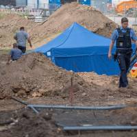 A policeman walks past a blue tent covering a British World War II bomb that was found during construction work on Wednesday in Frankfurt am Main, western Germany. The disposal of the bomb that is planned for Sunday requires the evacuation of around 70,000 people. | BORIS ROESSLER / DPA / VIA AFP-JIJI