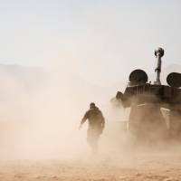 Hezbollah fighters walk near a tank in Western Qalamoun, Syria, Wednesday. | REUTERS