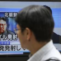 Passers-by watch a TV news program showing an image of North Korean leader Kim Jong Un, in Tokyo on Saturday. | AP