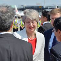 Japanese officials greet arriving British Prime Minister Theresa May at Itami Airport in Osaka Wednesday. | AFP-JIJI
