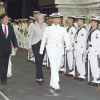 British Prime Minister Theresa May, along with Defense Minister Itsunori Onodera, reviews an honor guard on board the Maritime Self-Defense Force\'s helicopter carrier Izumo at Yokosuka base in Kanagawa Prefecture on Thursday. | POOL / VIA KYODO