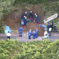 Investigators dig a hole beside a forest road in Taga, Shiga Prefecture, early this month in the search for the body of a Nagoya woman based on confessions given by two suspects. | KYODO