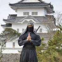 A man wearing a ninja costume has his photo taken with Ueno Castle in Iga, Mie Prefecture, in the background. A graduate school of Mie University is planning to introduce ninja studies as one its entrance exam subjects. | KYODO