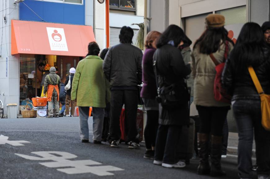 People wait in a line to collect food distributed by Second Harvest Japan.