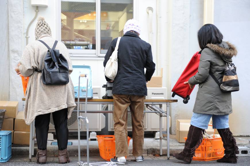 Left: People pack food distributed by Second Harvest Japan in bags before carrying them home.
