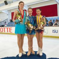 Riko Takino (right) stands on the podium with winner Alexandra Trusova (center) and second-place finisher Anastasiia Guliakova after earning the bronze medal at the Junior Grand Prix in Brisbane, Australia, on Saturday. | FACEBOOK