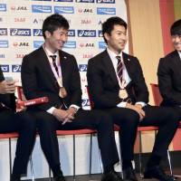 (From left) Japanese sprinters Kenji Fujimitsu, Yoshihide Kiryu, Shota Iizuka and Shuhei Tada take questions from reporters after the national team returned home from the IAAF World Athletics Championships at Haneda airport on Tuesday. They captured a bronze medal in the men’s 4x100-meter relay in London. | KAZ NAGATSUKA
