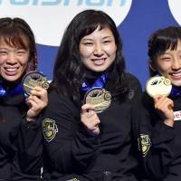 Winners (from left) Risako Kawai, Sara Dosho and Yui Susaki pose Thursday after winning gold medals in the world wrestling championships in Paris. | KYODO