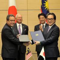 Malaysian Investment Development Authority (MIDA) CEO Azman Mahmud and Japan External Trade Organization (JETRO) Chairman Hiroyuki Ishige shake hands after signing a memorandum of cooperation in Tokyo on Nov. 16. | MIDA
