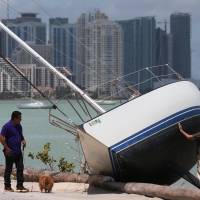 A man walks past a boat that went ashore after the passing of Hurricane Irma in Key Biscayne, Florida, Monday. | REUTERS