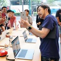 A shop employee briefs customers on the new features of the iPhone 8 handset at an Apple Store in the Omotesando district in Tokyo, as the product debuts in Japan on Friday. | KYODO