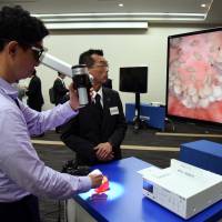 A reporter views sliced paprika using an advanced Orbeye microscope at a Sony Olympus Medical Solutions news conference on Tuesday. | SATOKO KAWASAKI