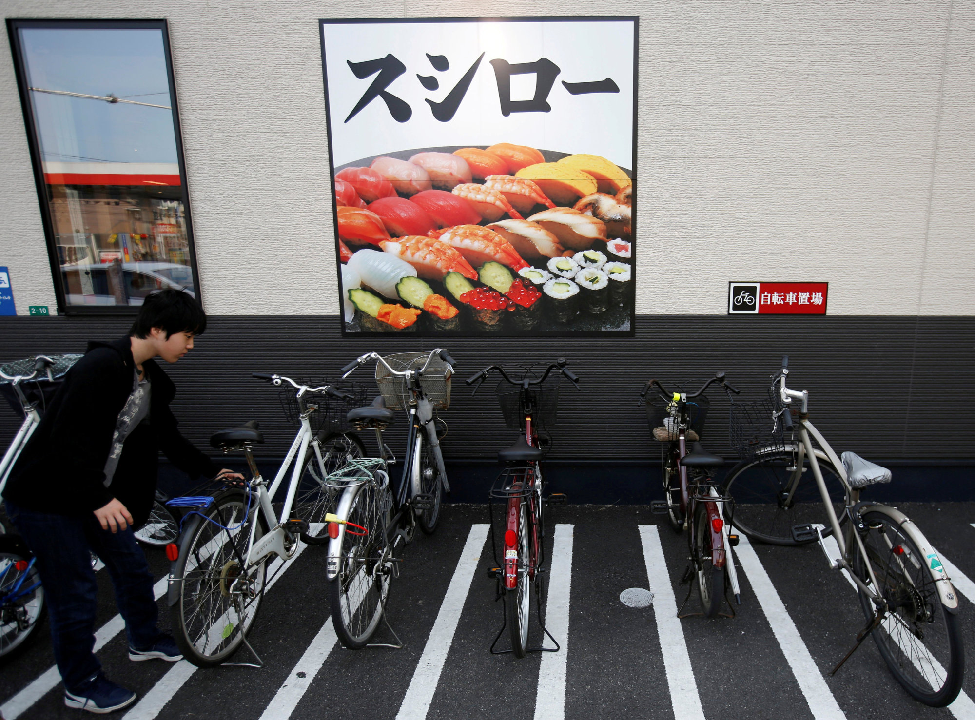 A customer parks a bicycle outside sushi restaurant chain Sushiro in Kawaguchi, Saitama Prefecture in May 2016. | REUTERS