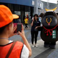 A visitor poses for a photographer with official cattle mascot Ushi-Masamune at the 11th National Japanese Beef Ability Expo in Sendai. | REUTERS